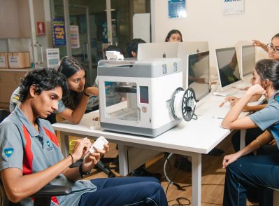 Students working on a 3D printing project in a modern classroom at one of the best international schools in Bangalore, using computers and hands-on models for STEM learning.