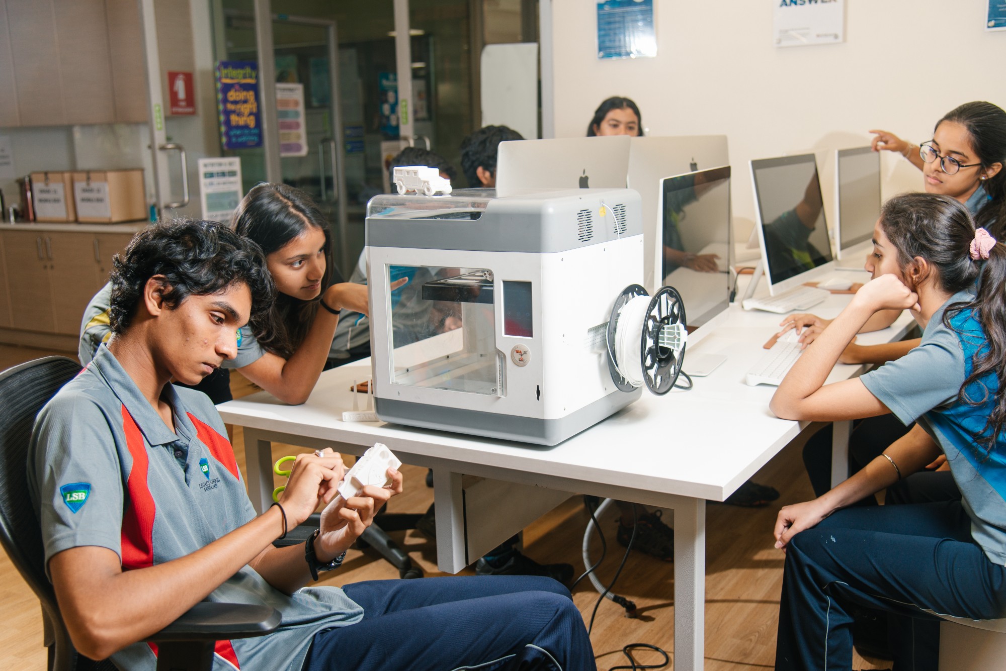 Students working on a 3D printing project in a modern classroom at one of the best international schools in Bangalore, using computers and hands-on models for STEM learning.